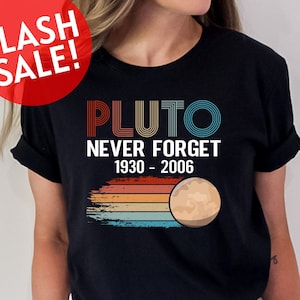 May include: A black t-shirt with a vintage-style graphic that says "Pluto Never Forget 1930-2006". The graphic features a stylized image of Pluto with a rainbow-colored background.