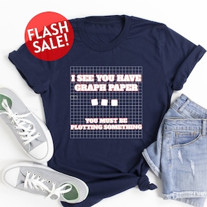 May include: A navy blue t-shirt with a white graphic that says "I see you have graph paper. You must be plotting something." The graphic is on a grid pattern.