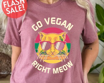 May include: A maroon t-shirt with a retro-style graphic of a cat wearing sunglasses. The graphic says "Go Vegan Right Meow".