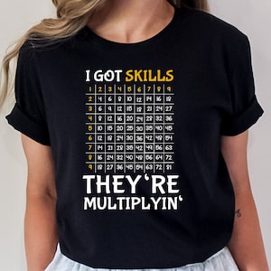 May include: Black t-shirt with the text "I GOT SKILLS" and a multiplication table printed in yellow. The text "THEY'RE MULTIPLYIN'" is printed below the table.