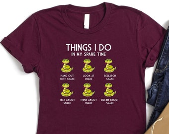May include: A maroon t-shirt with a white graphic that says "Things I do in my spare time" and features six cartoon snakes with text below each snake that says "Hang out with snake", "Look at snake", "Research snake", "Talk about snake", "Think about snake", and "Dream about snake".