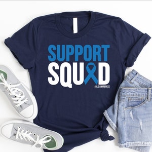 May include: A navy blue t-shirt with white text that reads "SUPPORT SQUAD" with a blue ribbon and the text "#ALS AWARENESS".