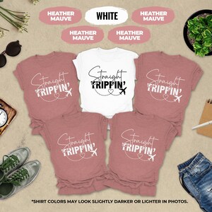 a collection of travel-themed items, including a white t-shirt with the text "Straight Tripin'", pink t-shirts, sunglasses, a clock, a plant, and a pair of jeans. The items are arranged on a beige background, creating a visually appealing and travel-inspired collage.