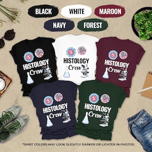 May include: A collection of t-shirts in black, white, maroon, navy, and forest green. Each shirt features the text "HISTOLOGY Crew" with a microscope and lab flask graphic. The shirts are displayed with accessories.