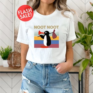 a woman wearing a white t - shirt with a picture of a penguin on it