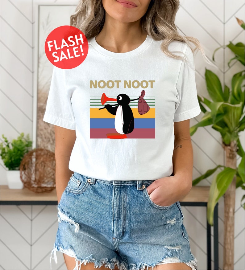 a woman wearing a white t - shirt with a picture of a penguin on it