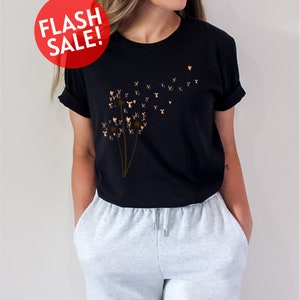 a woman wearing a black t - shirt with a dandelion design
