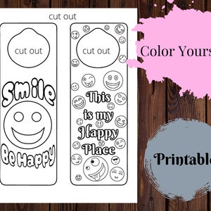 Könnte beinhalten: Druckbare Malvorlage mit zwei Lesezeichen. Das linke Lesezeichen hat ein Smiley-Gesicht und den Text "Smile Be Happy". Das rechte Lesezeichen hat den Text "This is my Happy Place" und ist von Smiley-Gesichtern umgeben. Beide Lesezeichen haben oben einen ausgeschnittenen Kreis.