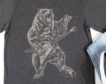 Puede incluir: Una camiseta gris oscuro jaspeada con un gráfico de un oso tocando una guitarra eléctrica. El oso es marrón y la guitarra es negra. La camiseta es talla L para hombre.