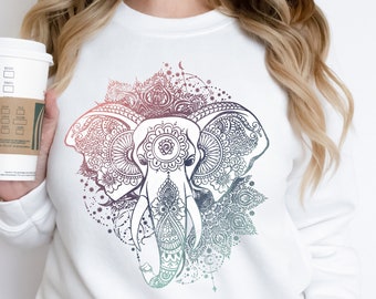 Puede incluir: Sudadera blanca con un diseño de mandala colorido con un elefante. El elefante está contorneado en negro y tiene un degradado de rosa, azul y verde.