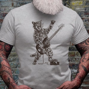 Może przedstawiać: Szary t-shirt z grafiką kota grającego na basie. Kot ma na sobie wz&oacute;r w panterkę i mikrofon w pysku.