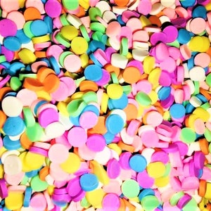 May include: A large assortment of colorful round sprinkles in various shades of pink, blue, green, yellow, and orange.