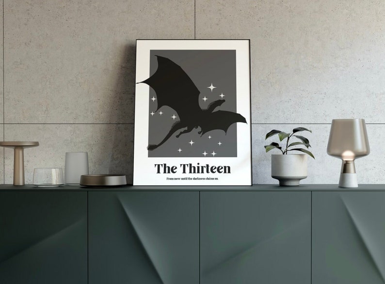May include: A black and white poster featuring a silhouette of a dragon flying against a dark grey background with white stars. The poster has the text "The Thirteen" and the text "From now until the darkness claims us."