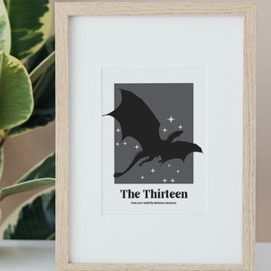May include: A framed print featuring a black silhouette of a dragon flying against a dark grey background with white stars. The text "The Thirteen" is below the dragon with the caption "From now until the darkness claims us."