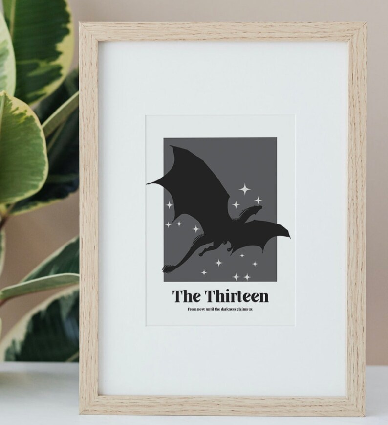 May include: A framed print featuring a black silhouette of a dragon flying against a dark grey background with white stars. The text "The Thirteen" is below the dragon with the caption "From now until the darkness claims us."
