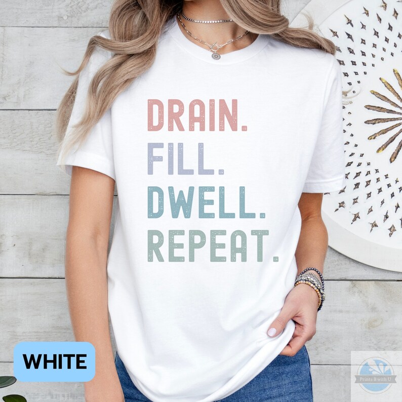 May include: White t-shirt with the text "DRAIN. FILL. DWELL. REPEAT." in a vintage style font with pastel colors.