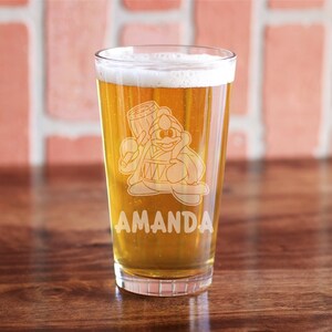 May include: A clear glass beer stein with a cartoon character holding a drum and the name "AMANDA" etched on the side.
