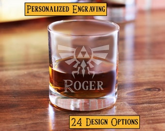 May include: A clear glass whiskey tumbler with an engraved Triforce symbol and the name "ROGER". The glass is filled with amber liquid and sits on a wooden surface. The text "PERSONALIZED ENGRAVING" appears above the glass and "24 DESIGN OPTIONS" appears below the glass.