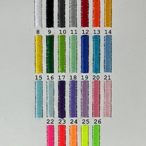 May include: A color chart featuring twenty-six vertical rectangular embroidery thread swatches arranged in rows. Each swatch is numbered from 1 to 26, displaying a wide spectrum of colors including white, black, grays, reds, oranges, yellows, greens, blues, purples, and pinks.