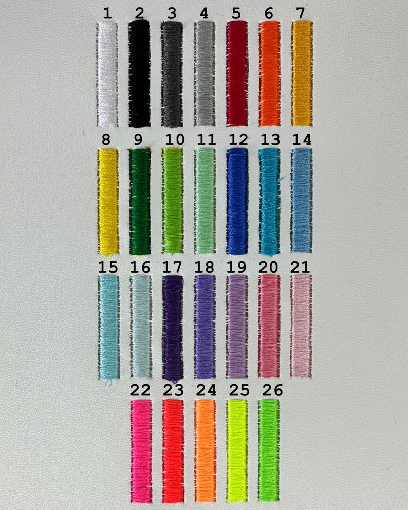 May include: A color chart featuring twenty-six vertical rectangular embroidery thread swatches arranged in rows. Each swatch is numbered from 1 to 26, displaying a wide spectrum of colors including white, black, grays, reds, oranges, yellows, greens, blues, purples, and pinks.