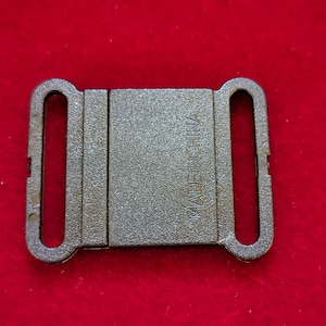 May include: Black plastic buckle with a textured surface and the words "Made in China" printed on the front.