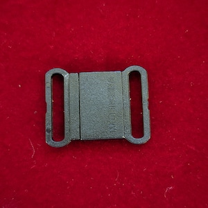 Peut inclure: Une boucle coulissante en plastique noir avec les mots "MADE IN CHINA" en relief sur le devant.