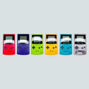Może przedstawiać: Kolekcja sześciu przenośnych konsol do gier Game Boy Color w różnych kolorach. Konsole są czerwone, fioletowe, zielone, żółte, niebieskie i przezroczyste fioletowe. Każda konsola ma ekran, przyciski i napis "GAME BOY COLOR" u góry.