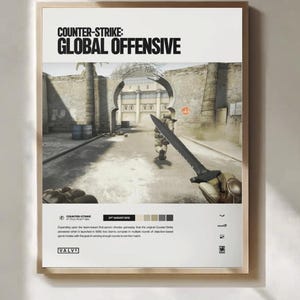 May include: A framed poster for the video game "Counter-Strike: Global Offensive." The poster features a game scene with a soldier holding a knife. The title is at the top, with the game's release date and the Valve logo at the bottom.