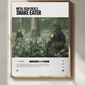 May include: Framed poster for "Metal Gear Solid 3: Snake Eater." The poster displays the game's title in black above a forest scene with two figures. The poster is in a wooden frame, with the date 17th November 2004.