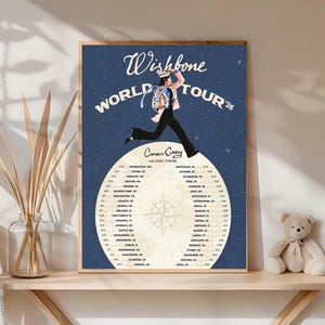 Könnte beinhalten: Gerahmtes Poster im Vintage-Stil mit der Aufschrift "Wishbone World Tour '26" und einer Abbildung einer springenden Person. Das Poster enthält eine Liste von Tourdaten und -orten. Das Farbschema ist hauptsächlich Marineblau und Creme.