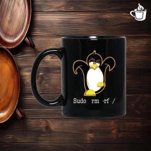 Puede incluir: Taza de cerámica negra con un diseño de pingüino de dibujos animados en amarillo y blanco. El texto "Sudo rm -rf /" está impreso debajo. La taza tiene un asa curva. Fondo de madera.