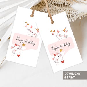 Op de afbeelding: Twee witte cadeaulabels met een cartoon kat illustratie. Elk label heeft een kat met een feesthoed en een tekstballon met de woorden "happy birthday". Kleine hartjes en een eenhoornhoorn zijn ook inbegrepen.