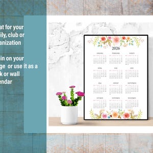 May include: Printable 2026 calendar with floral design. The calendar is framed and sitting on a white shelf. The calendar has a floral design at the top and bottom. The months are listed in a grid format.