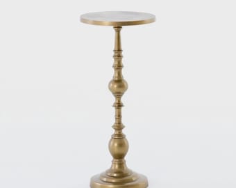 Op de afbeelding: Een goudkleurige, sierlijke bijzettafel met een rond blad. De tafel heeft een decoratieve, gedetailleerde stam met een ronde voet. De tafel is ongeveer 71 cm hoog.