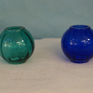 May include: Two small glass vases, one teal blue and one cobalt blue, with a ribbed design.