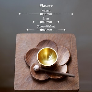 May include: A wooden flower-shaped base with a brass bowl and a wooden mallet. The base is made of walnut and measures 95mm in diameter. The brass bowl is 40mm in diameter. The mallet has a stone and walnut head, 83mm in diameter.