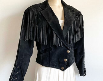 May include: Black suede jacket with fringe detailing on the shoulders and a cropped, fitted silhouette.