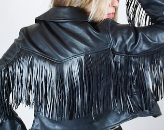 May include: Black leather jacket with fringe detailing. The jacket has a cropped fit and a collar.