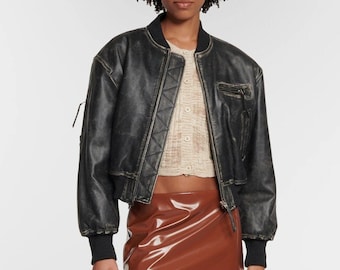 May include: A black leather bomber jacket with a brown patent leather mini skirt and brown snakeskin knee-high boots.