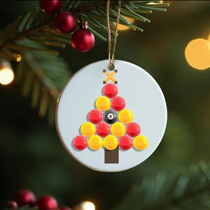 May include: A white ceramic Christmas bauble shaped like a Christmas tree with a pool ball design. The tree is decorated with red and yellow pool balls, with the 8 ball at the top.