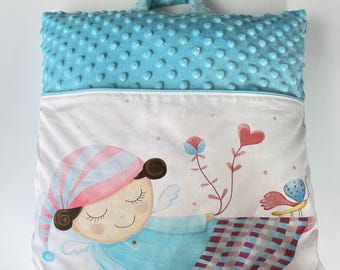 Pode incluir: Um travesseiro azul claro e branco com uma alça. O travesseiro tem um fundo branco com uma ilustração de desenho animado de um anjo dormindo com pijama listrado rosa e branco, um coração rosa e uma borboleta. O travesseiro é feito de tecido macio e felpudo.
