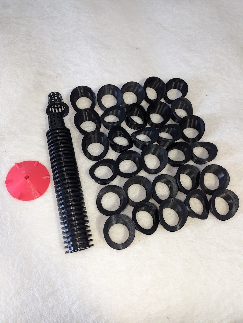 Op de afbeelding: Een set zwarte plastic hydroponische netpotten met een rode irrigatie-emitter en een zwarte irrigatieslang. De netpotten zijn in een halve cirkel gerangschikt.