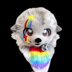 May include: A furry, light gray animal head with large, expressive eyes and a black nose. A rainbow design with a yellow star accents the forehead and cheek. A rainbow-colored section adorns the neck, and a gray bow is at the base of the neck.