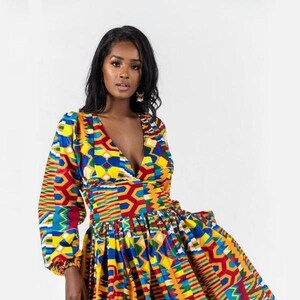 Peut inclure: Une robe longue à manches longues avec un décolleté en V et une jupe asymétrique. La robe présente un motif géométrique vibrant dans des tons de rouge, jaune, bleu et vert.