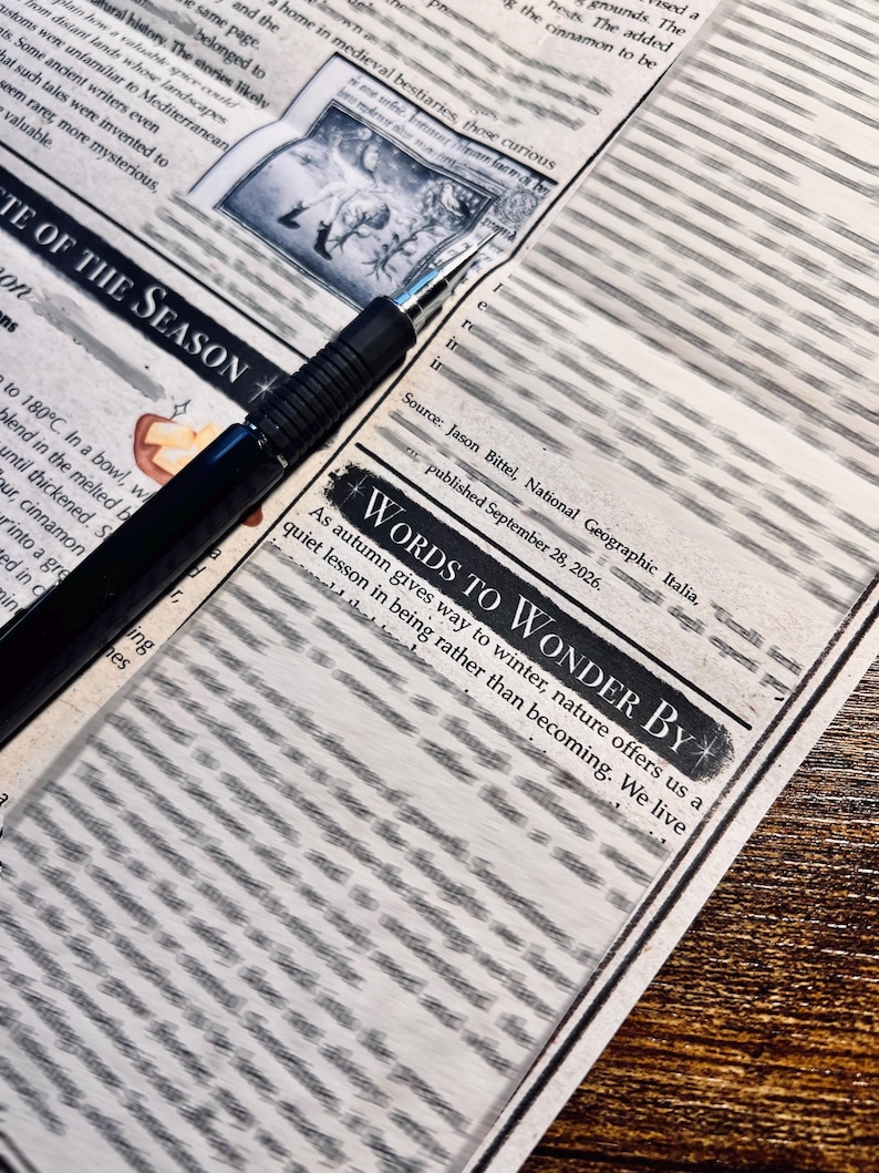 May include: A black fountain pen rests diagonally across a printed page featuring the text "WORDS TO WONDER BY" and "NOTE OF THE SEASON." The paper contains columns of text, a small illustration, and a source citation dated September 28, 2026.