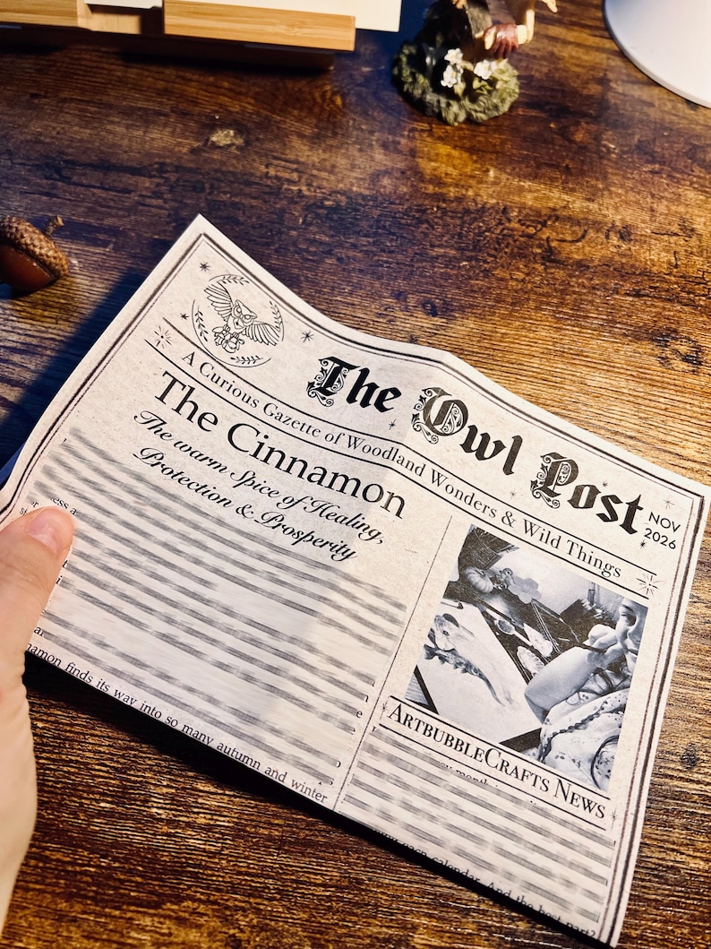 May include: A printed paper titled The Owl Post, dated Nov 2026, featuring the headline The Cinnamon: The warm Spice of Healing, Protection & Prosperity. It includes an owl illustration, a black and white image, and ArtBubbleCrafts News text.