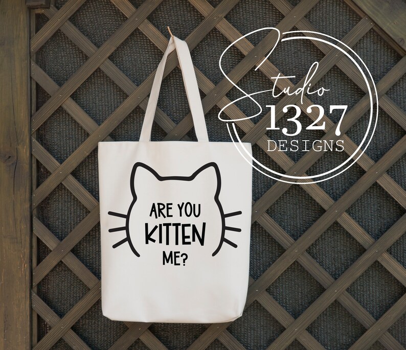 May include: White tote bag with black cat ears and the text "Are you kitten me?" printed on the front.