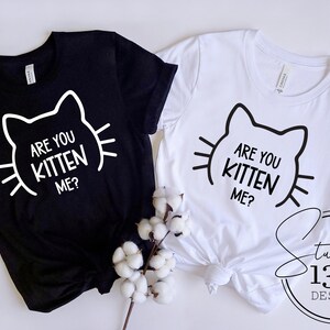 May include: Two t-shirts, one black and one white, with the text "Are you kitten me?" and a stylized cat face graphic.