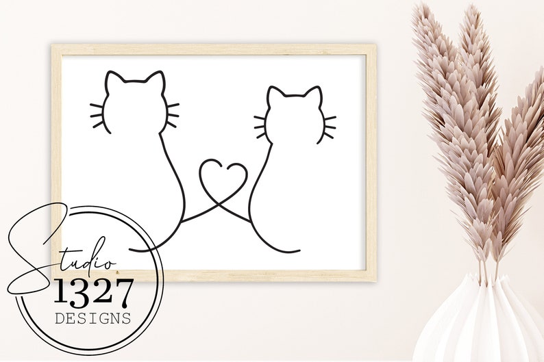 May include: Line art print of two cats with their tails intertwined to form a heart shape. The print is in a light wood frame and is hanging on a white wall.
