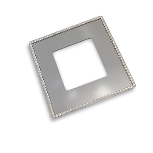 Puede incluir: Una tapa de interruptor de luz plateada con un borde de cristal transparente.
